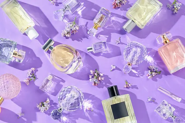 Düz kompozisyon, parfüm şişeleri ve mor arka planda leylak çiçekleri vardı.