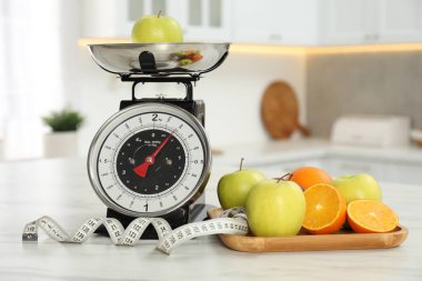 Meyveli mutfak pulları ve kapalı alandaki hafif mermer masada mezura.