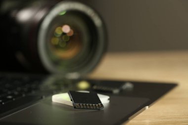 SD hafıza kartı, tutucu, dizüstü bilgisayar ve fotoğraf makinesi ahşap masada, yakın plan.