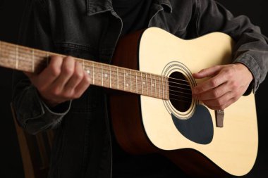 Siyah arkaplanda gitar çalan adam, yakın plan
