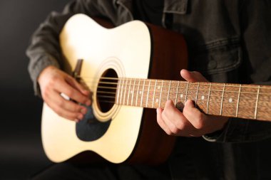 Siyah arkaplanda gitar çalan adam, yakın plan