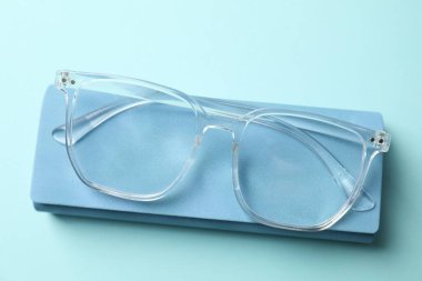 Açık mavi arka planda şık gözlüklü çanta, üst görünüm