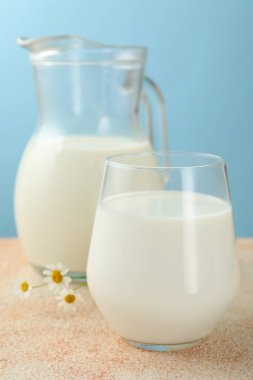 Taze süt ve çiçekler açık mavi arkaplanda, yakın plan