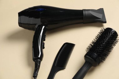 Bej arka planda yuvarlak fırça, tarak ve kurutucu, üst görünümde