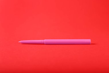 Kırmızı arkaplanda bir göz kalemi, yakın plan.