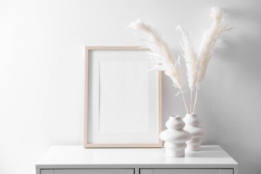 Beyaz duvarın yanındaki dolapta boş resim çerçevesi ve şık ev dekorasyonu