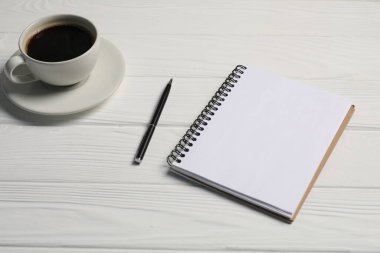 Not defteri, kalem ve kahve beyaz ahşap masada, yakın plan.