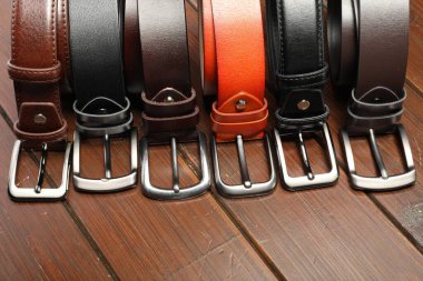 Ahşap masanın üstünde birçok deri kemer var.