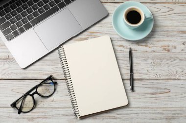 Kalemli, dizüstü bilgisayarlı, bardaklı ve kahveli defter beyaz ahşap masada, düz yatıyordu.