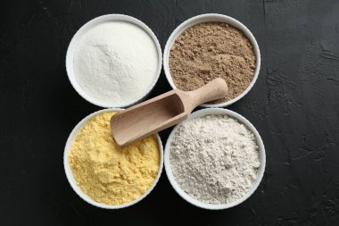Kâselerdeki farklı un türleri ve siyah desenli masa, üst görünüm.
