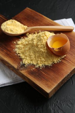 Mısır unu yığını, kaşık ve kırık yumurta siyah desenli masa, yakın plan.