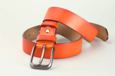 Beyaz arka planda turuncu bir deri kemer, yakın plan.