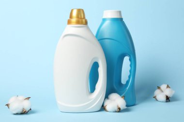 Bir şişe yumuşatıcı ve açık mavi arka planda pamuk çiçekleri.