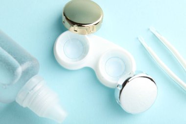 Işık turkuaz arka planda kontak lensler, çözüm ve cımbızlar düz konum