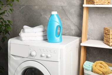 Bir şişe yumuşatıcı ve çamaşır makinesinin üzerindeki havlular.
