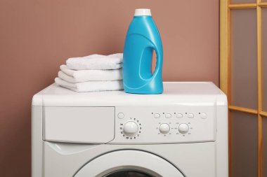 Bir şişe yumuşatıcı ve çamaşır makinesinin üzerindeki havlular.
