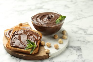 Çikolata, naneli ve fındıklı beyaz mermer masa, yakın plan.