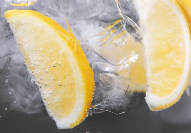 Koyu arkaplanda limon dilimleri ve buzla soda tazeleniyor. Yakın plan.