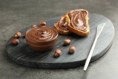 Lezzetli çikolatalı tostlar ve gri desenli masada fındıklar, yakın plan.