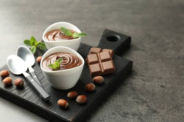 Lezzetli çikolata, parçalar, nane ve fındık. Gri desenli masa, yakın plan.