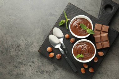 Lezzetli çikolata, parçalar, nane ve fındıklar gri desenli masa, üst manzara. Metin için boşluk