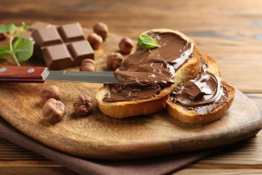 Lezzetli çikolatalı tostlar, parçalar, nane ve fındıklar ahşap masada, yakın plan.