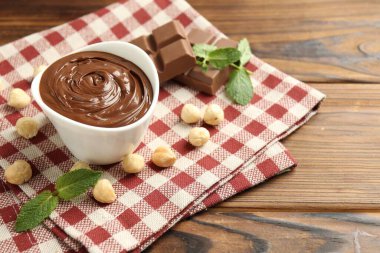 Lezzetli çikolata, parçalar, nane ve fındıklar ahşap masada, yakın plan.