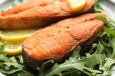 Deniz ürünleri. Lezzetli somon biftekleri, roka ve limon masada, yakın plan.