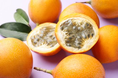 Olgun sarı çarkıfelek meyveleri ve yaprakları leylak arka planda, yakın plan