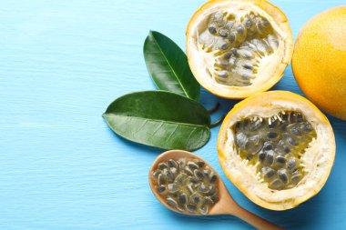 Olgun çarkıfelek meyveleri, yeşil yapraklar ve tohumlar açık mavi ahşap masada, manzaranın üstünde. Metin için boşluk