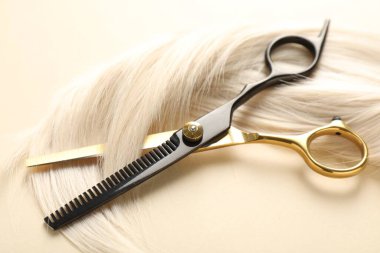 Bej arkaplanda saç tokası ve makas, yakın plan.