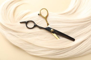 Bej arka planda saç kilidi ve makas, üst görünüm