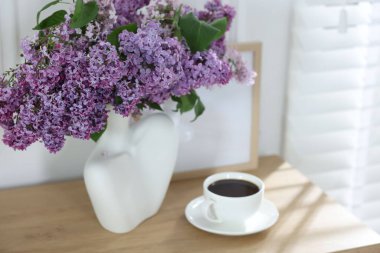 Güzel leylak çiçekleri ve ahşap masada kahve.