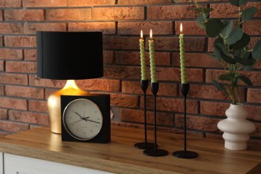 Mum ve tuğla duvarın yanındaki masada yanan mumlar.