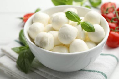 Lezzetli mozzarella peynir topları kasede fesleğen ve domatesler masada, yakın plan.