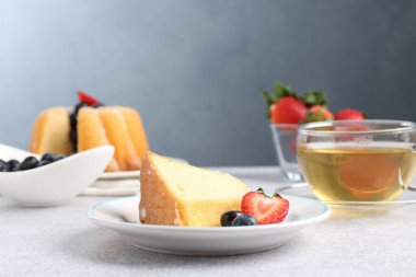 Açık gri masada böğürtlenli kek ve çay, yakın plan.