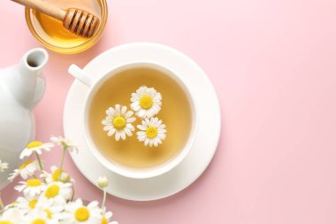 Fincanda nefis papatya çayı, taze çiçekler ve pembe arka planda bal, düz yatak. Metin için boşluk