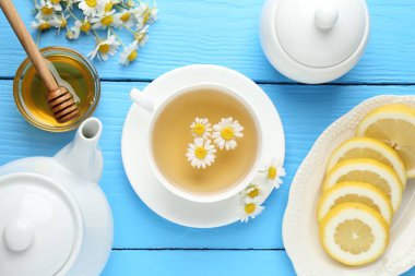 Lezzetli papatya çayı, taze çiçekler, limon ve bal açık mavi ahşap masa, düz uzanmış
