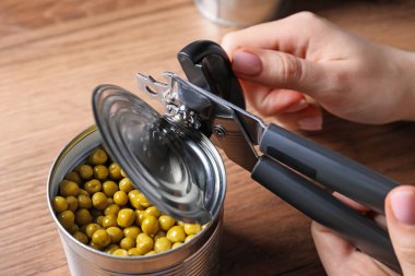 Yeşil bezelye konservesi açan kadın tahta masada konserve açacağıyla, yukarıda.