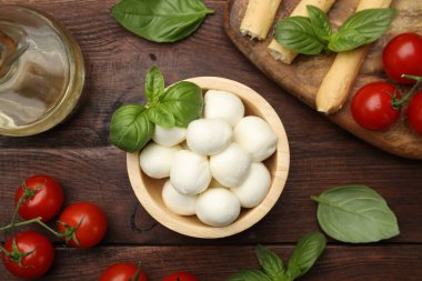 Lezzetli mozzarella peyniri topları, domates ve fesleğen ahşap masada, düz yerde.