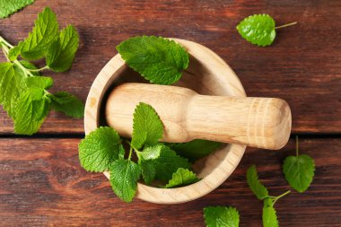 Taze limon merhemi yaprakları, ahşap masa üzerinde tokmak ve harç, düz uzanma