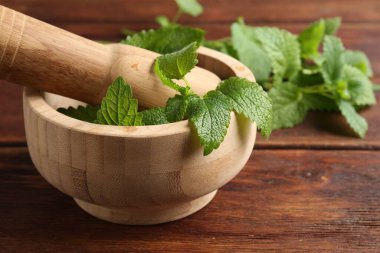 Taze limon merhemi yaprakları, ahşap masada tokmak ve havan topu, yakın plan.