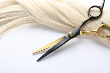 Beyaz zemin üzerinde saç kilidi ve makas, üst görünüm