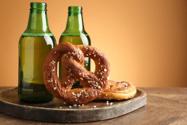 Lezzetli krakerler ve bira şişeleri ahşap masa üzerinde bej renkli gradyan arka plan, yakın çekim