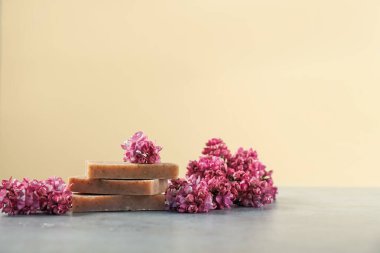 Bej arka planda gri masada bir yığın sabun ve leylak çiçeği. Metin için boşluk