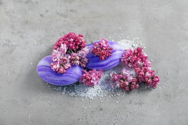 Gri desenli masada sabun, deniz tuzu ve leylak çiçekleri.