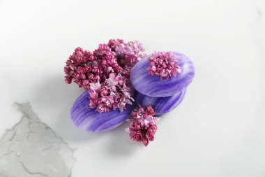 Beyaz mermer masada sabun çubukları ve leylak çiçekleri.