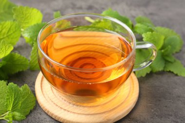 Cam bardakta Aromatik limon merhemi çayı ve gri masada taze yapraklar, yakın plan.