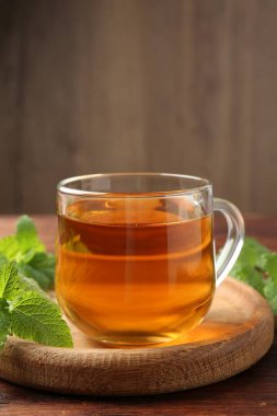 Cam bardakta Aromatik limon merhemi çayı ve ahşap masada taze yapraklar.