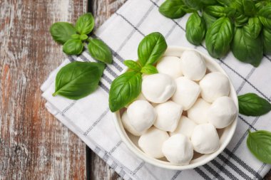 Lezzetli mozzarella peynir topları kasede ve fesleğen tahta masada, düz yerde. Metin için boşluk